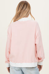 woman wearing a light pink striped oversized sweatshirt with white cuffs and hem, shown from the back