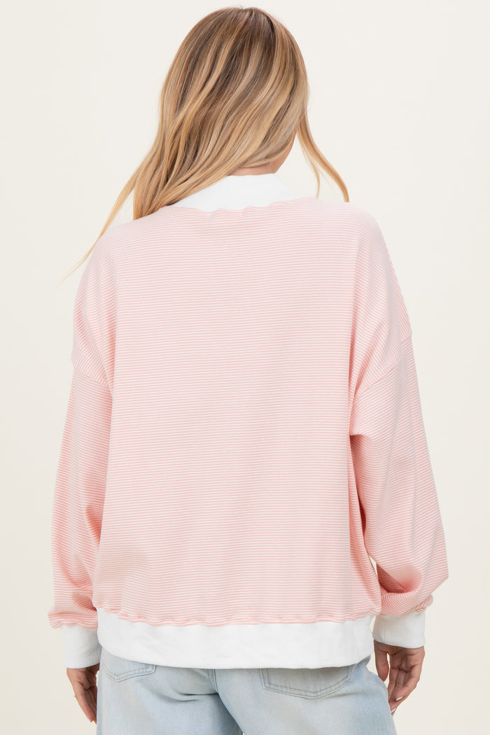 woman wearing a light pink striped oversized sweatshirt with white cuffs and hem, shown from the back