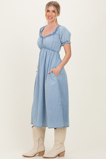 woman wearing a light blue puff sleeve denim maxi dress with pockets and styled with knee-high beige boots