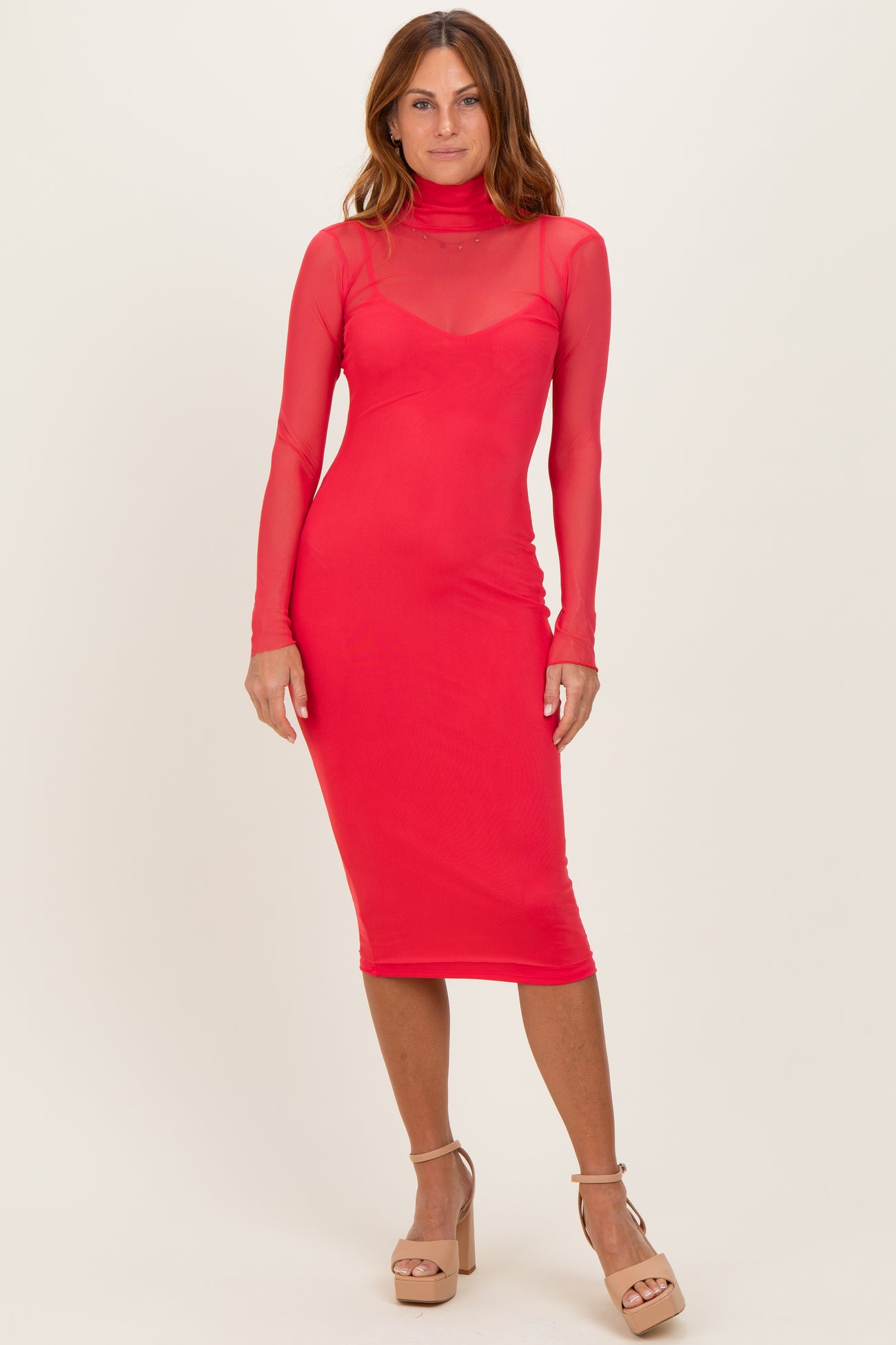 woman wearing a fitted red long sleeve mesh dress with a high neckline and a midi length