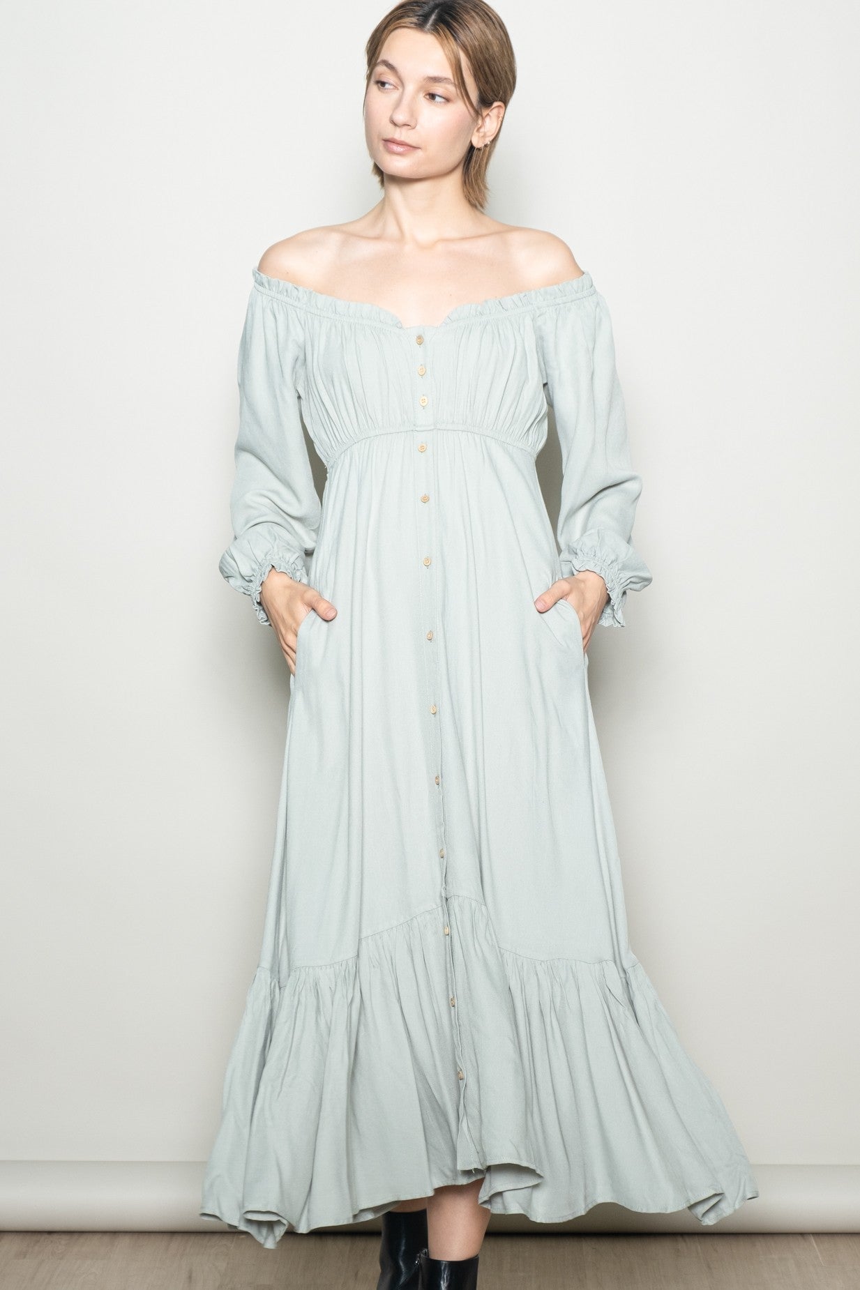 woman wearing a light green off-the-shoulder maxi dress with button details and pockets