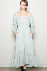 woman wearing a light green off-the-shoulder maxi dress with button details and pockets