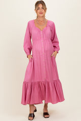 woman wearing a pink long sleeve maternity dress with buttons and pockets, featuring a tiered skirt and a baby bump