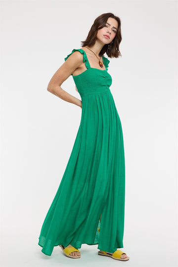 woman wearing a green maxi dress with ruffle straps and a fitted bodice, standing on a white background