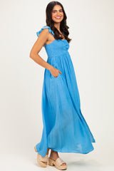 woman wearing a light blue maxi dress with ruffled straps and pockets, standing and smiling