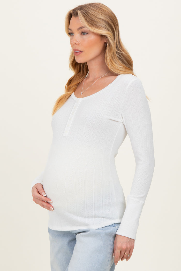 woman wearing a white long sleeve maternity top with a scoop neckline and a visible baby bump