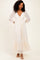 woman wearing a cream lace maxi dress with a deep V-neck and long sleeves, standing against a neutral background