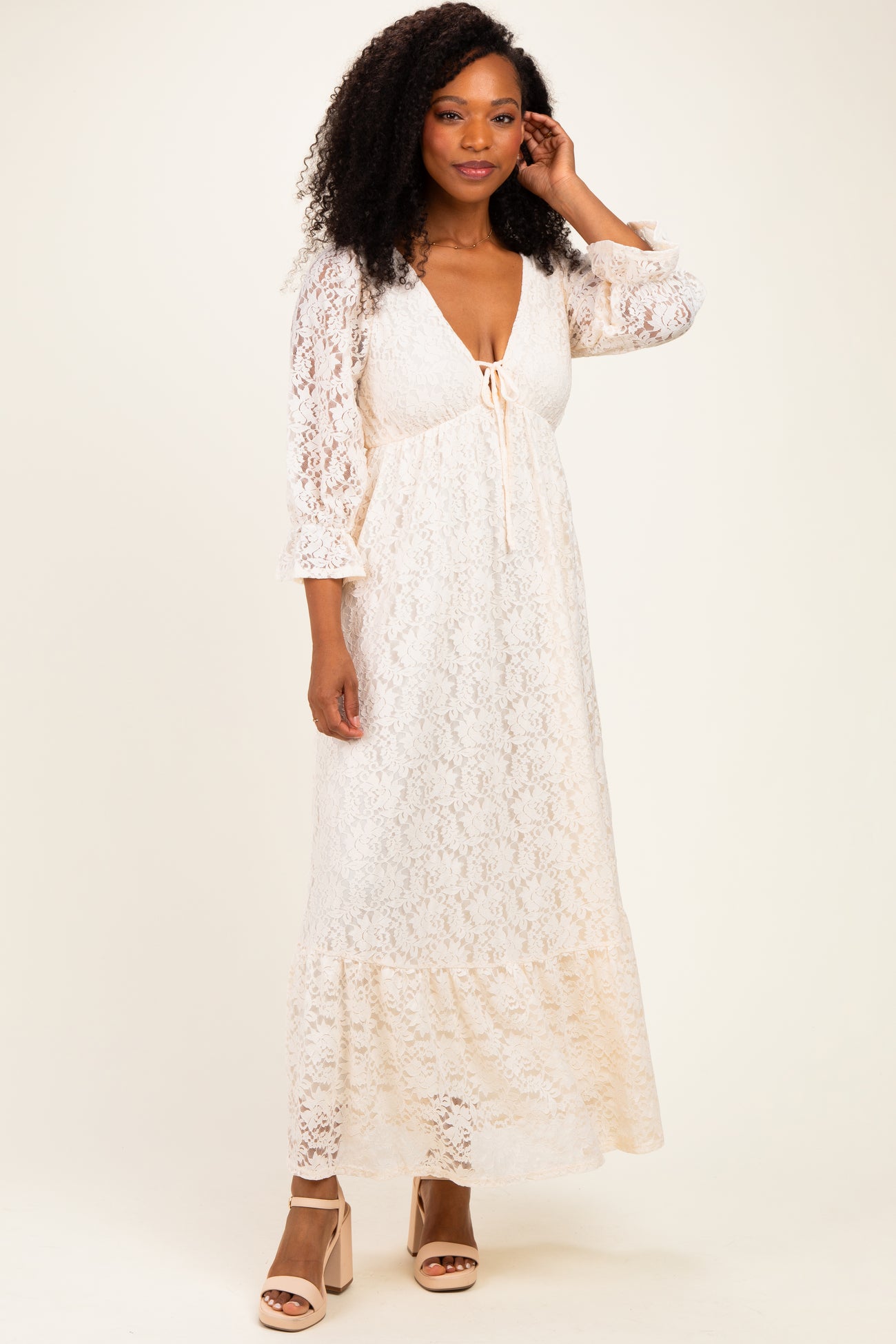 woman wearing a white lace maxi dress with a tie front and bell sleeves