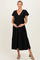 woman wearing a black maternity dress with puff sleeves and a tiered skirt, gently cradling her baby bump
