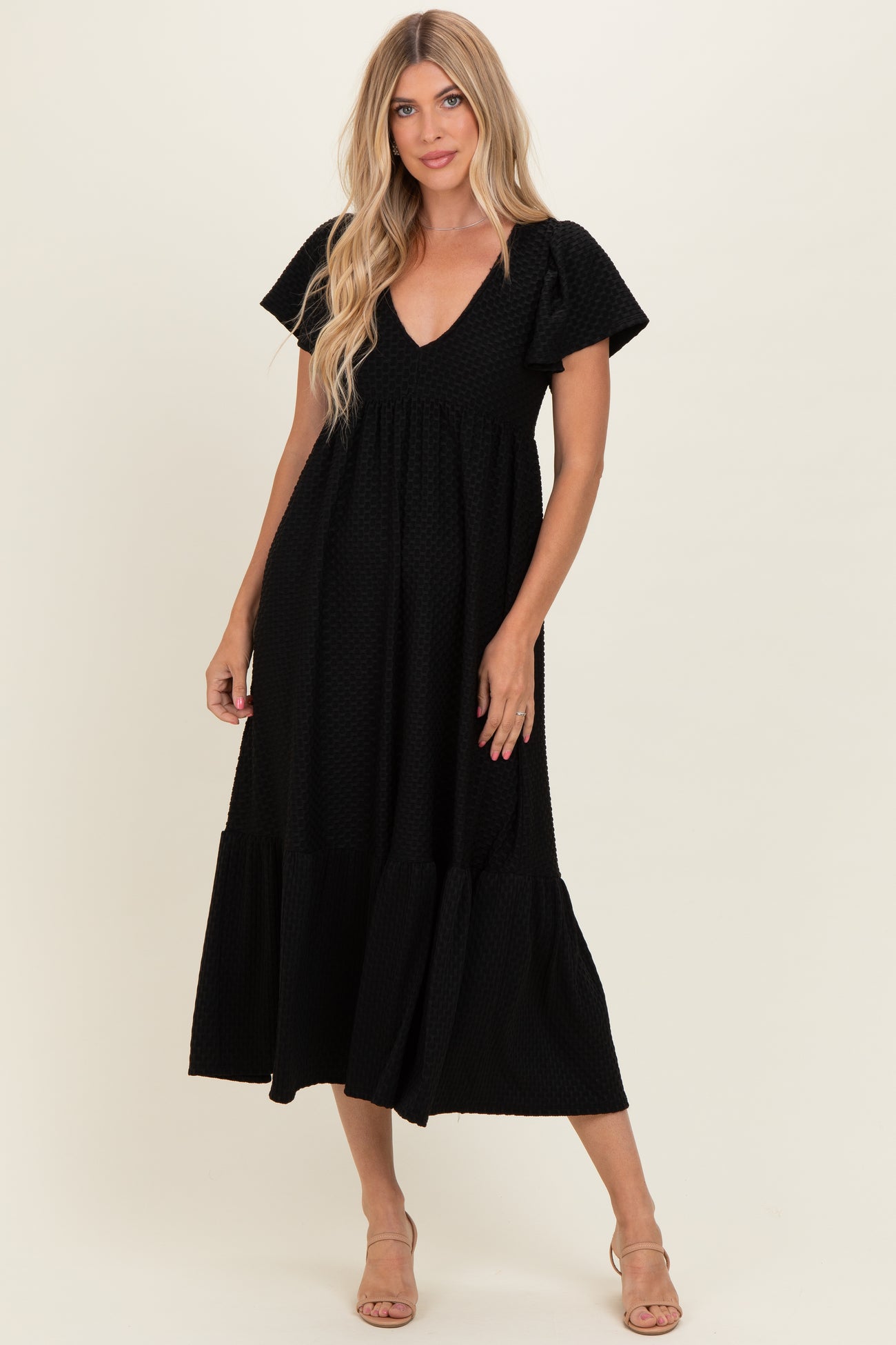 woman wearing a black tiered maxi dress with a v-neck and short puff sleeves