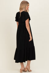 woman wearing a black short sleeve maxi dress with ruffle details, showing the back view and styled with sandals