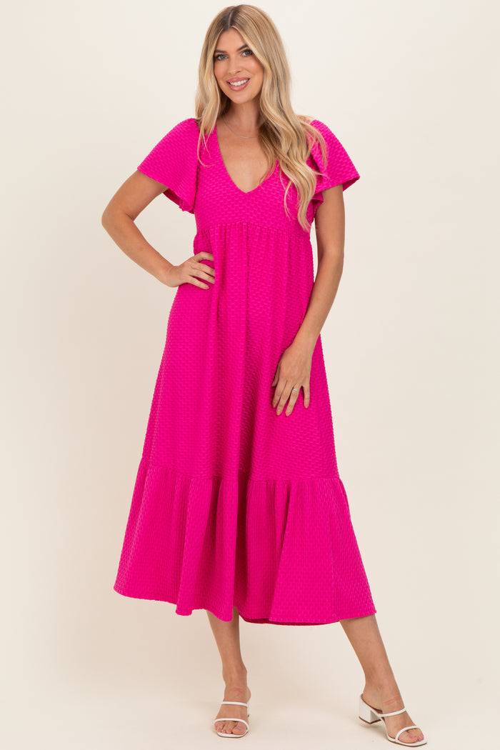 woman wearing a bright pink short sleeve maxi dress with a tiered hem and v-neckline