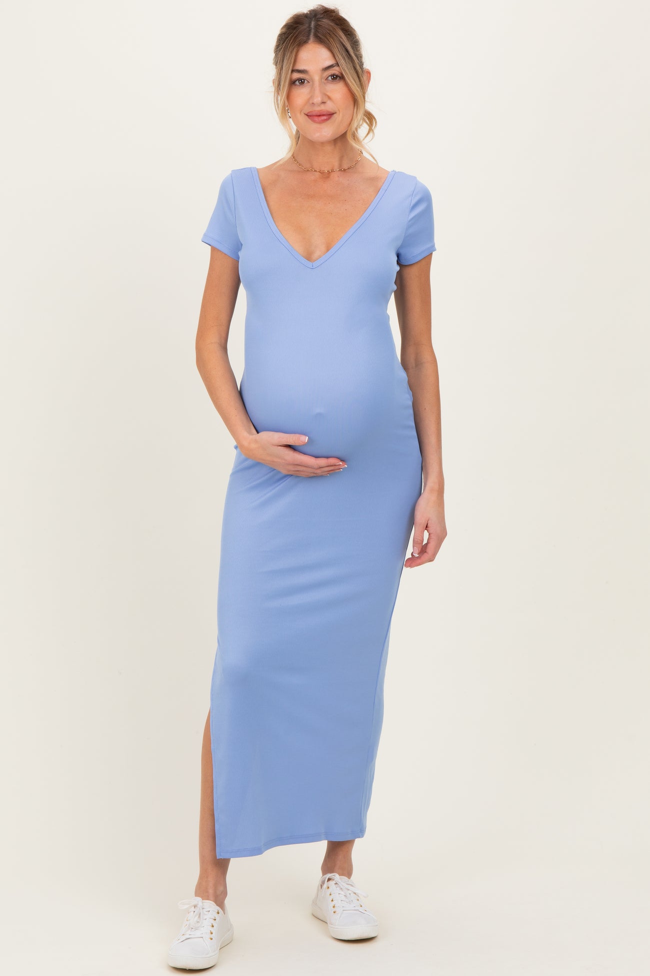 woman wearing a light blue maternity dress with a deep v-neck and side slit, showing her baby bump