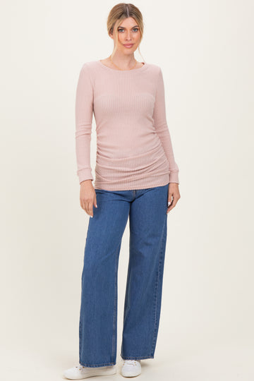 woman wearing a light pink ribbed long sleeve top with side ruching and wide leg denim jeans