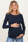 woman wearing a navy long sleeve maternity top, smiling while holding her baby bump