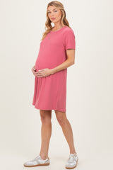 woman wearing a pink short sleeve maternity dress and holding her baby bump