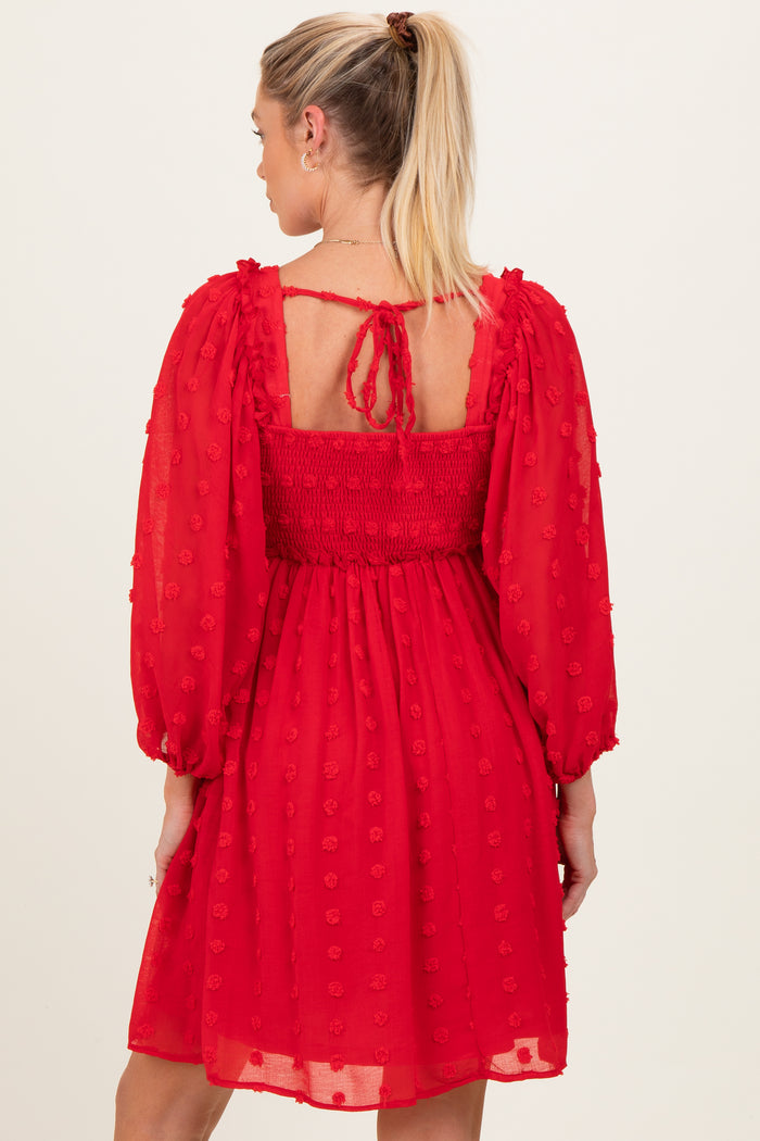 woman wearing a red maternity dress with puff sleeves and a smocked back, featuring textured floral details