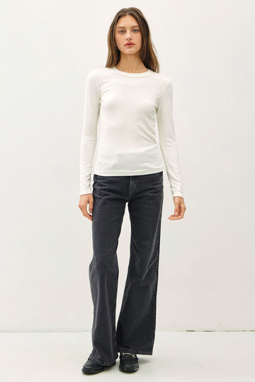 woman wearing a white long sleeve fitted top and black flared jeans