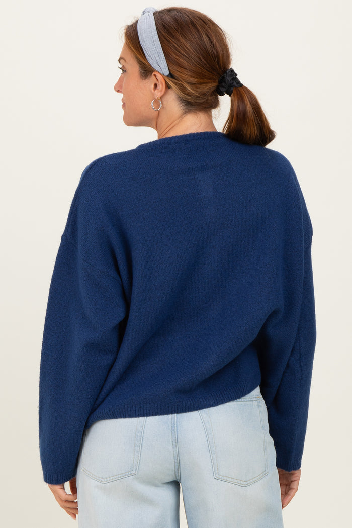 woman wearing a navy blue oversized sweater with a relaxed fit and back seam detail, styled with light blue jeans.