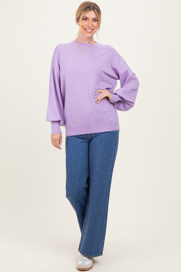 woman wearing a lavender oversized sweater and wide-leg blue jeans, styled with white sneakers