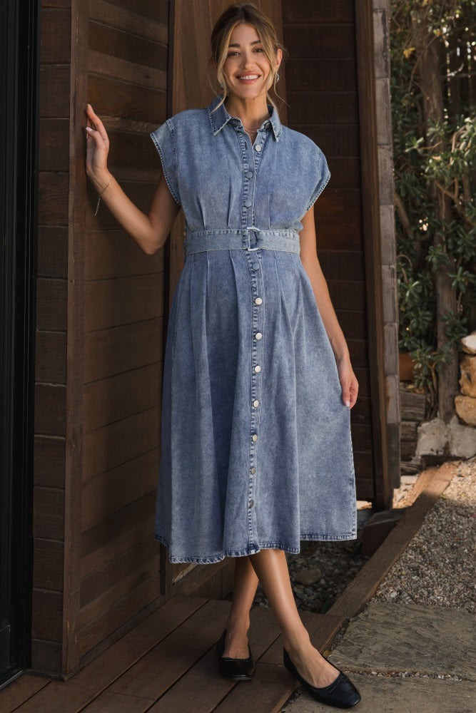woman wearing a light blue denim maternity dress with a belted waist and short sleeves, showcasing her baby bump