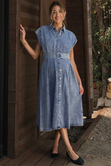 woman wearing a light blue denim maternity dress with a belted waist and short sleeves, showcasing her baby bump