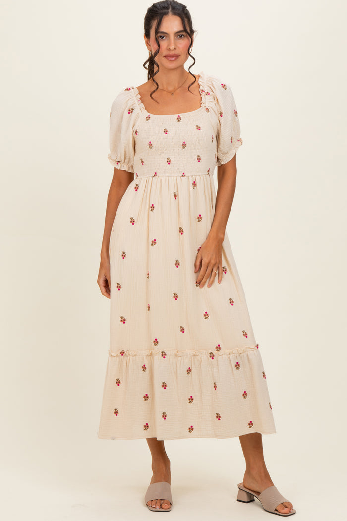 woman wearing a cream puff sleeve midi dress with floral print and ruffle hem, paired with gray slip-on mules