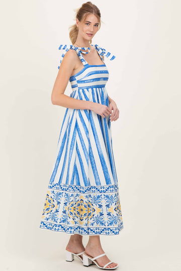 woman wearing a blue and white striped maxi dress with floral detailing and bow straps