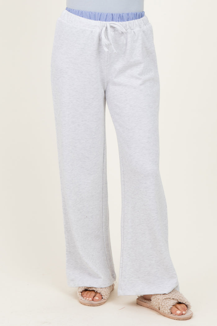 woman wearing light gray lounge pants with a drawstring waistband and a relaxed fit, paired with fuzzy slippers