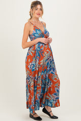 woman wearing an orange floral maternity maxi dress with a tiered skirt and spaghetti straps, showing her baby bump