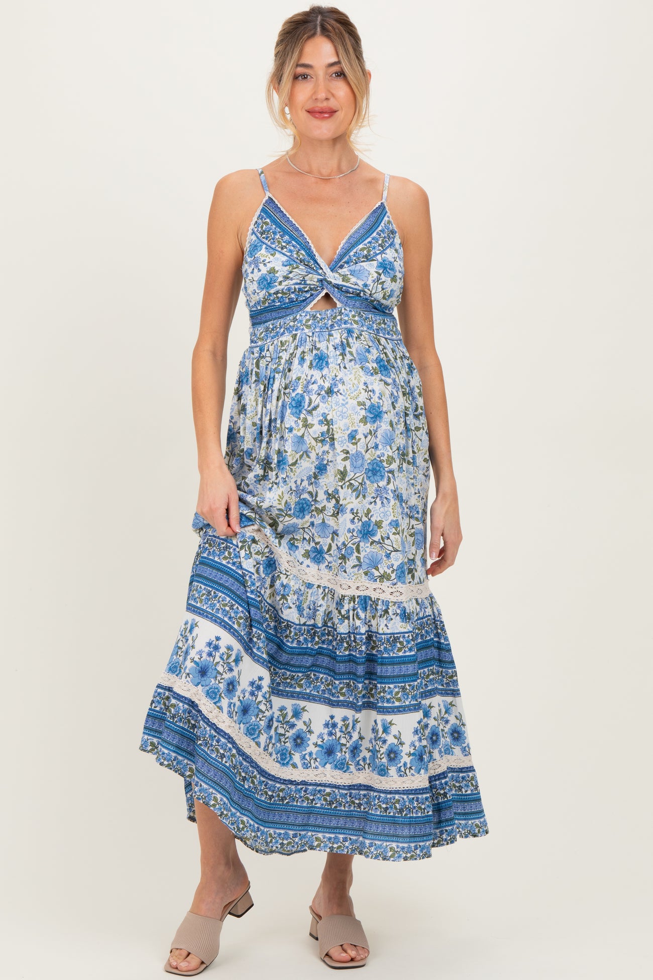 woman wearing a blue floral maternity maxi dress with a tie front detail and a flowing skirt, showcasing her baby bump