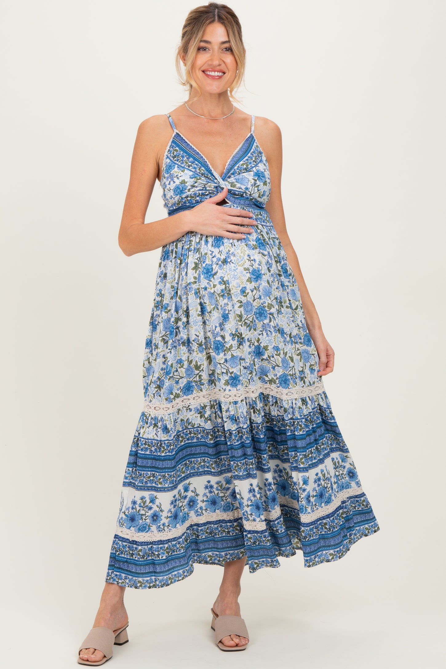 woman wearing a blue floral maternity maxi dress and holding her baby bump