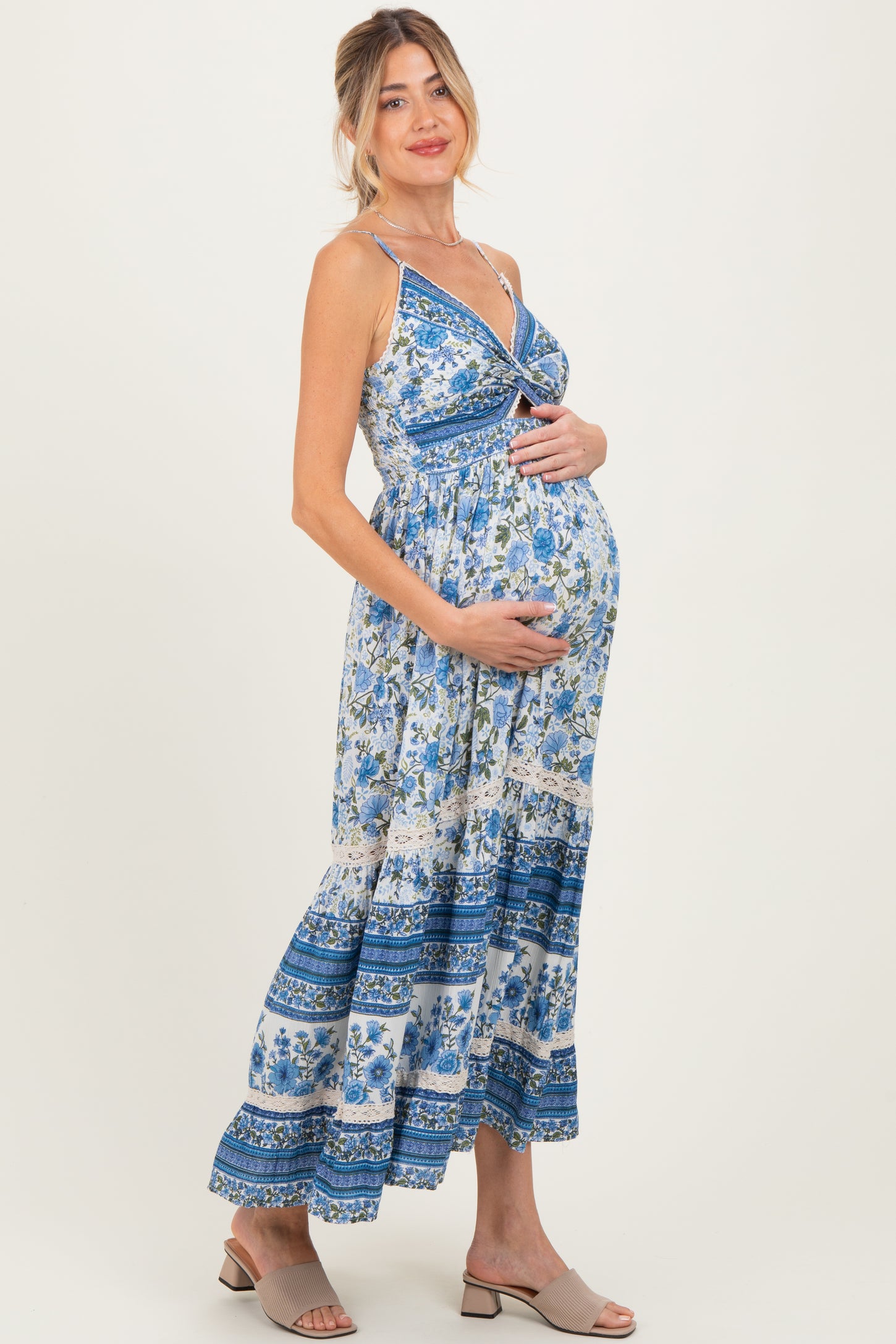 woman wearing a floral print maternity maxi dress with a knotted front and holding her baby bump