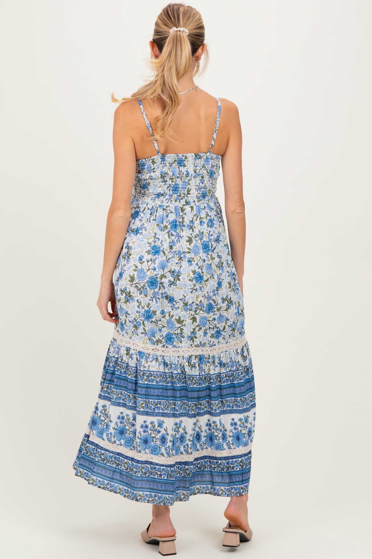 woman wearing a floral maternity maxi dress with blue and white patterns, showing a relaxed fit and adjustable straps