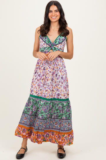 woman wearing a floral maxi dress with a fitted bodice and tiered skirt in vibrant colors