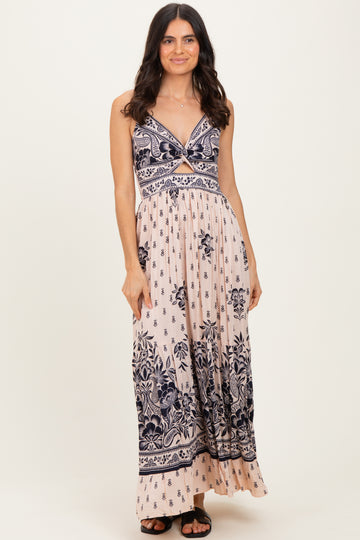woman wearing a light pink floral maxi dress with navy blue patterns and a crisscross bodice