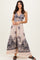 woman wearing a floral patterned maxi dress with a fitted bodice and flowing skirt in blush and navy colors