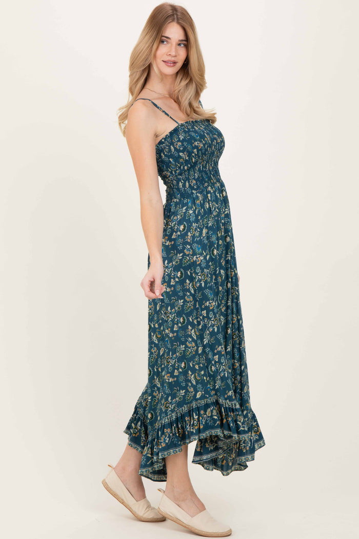 woman wearing a teal floral maxi dress with a ruffled hem and spaghetti straps