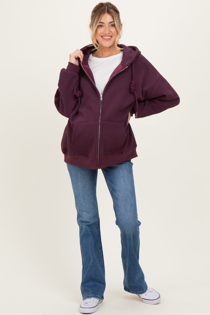 woman wearing a burgundy maternity zip-up hoodie with a white t-shirt and blue flared jeans