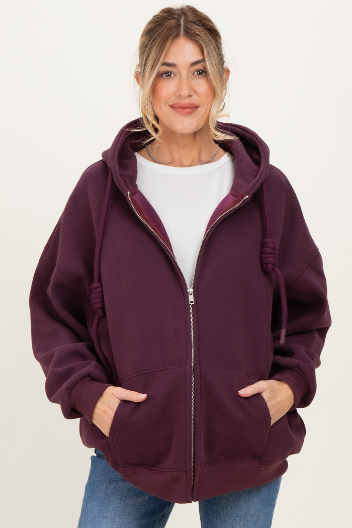 woman wearing a dark purple maternity zip-up hoodie with oversized fit and pockets