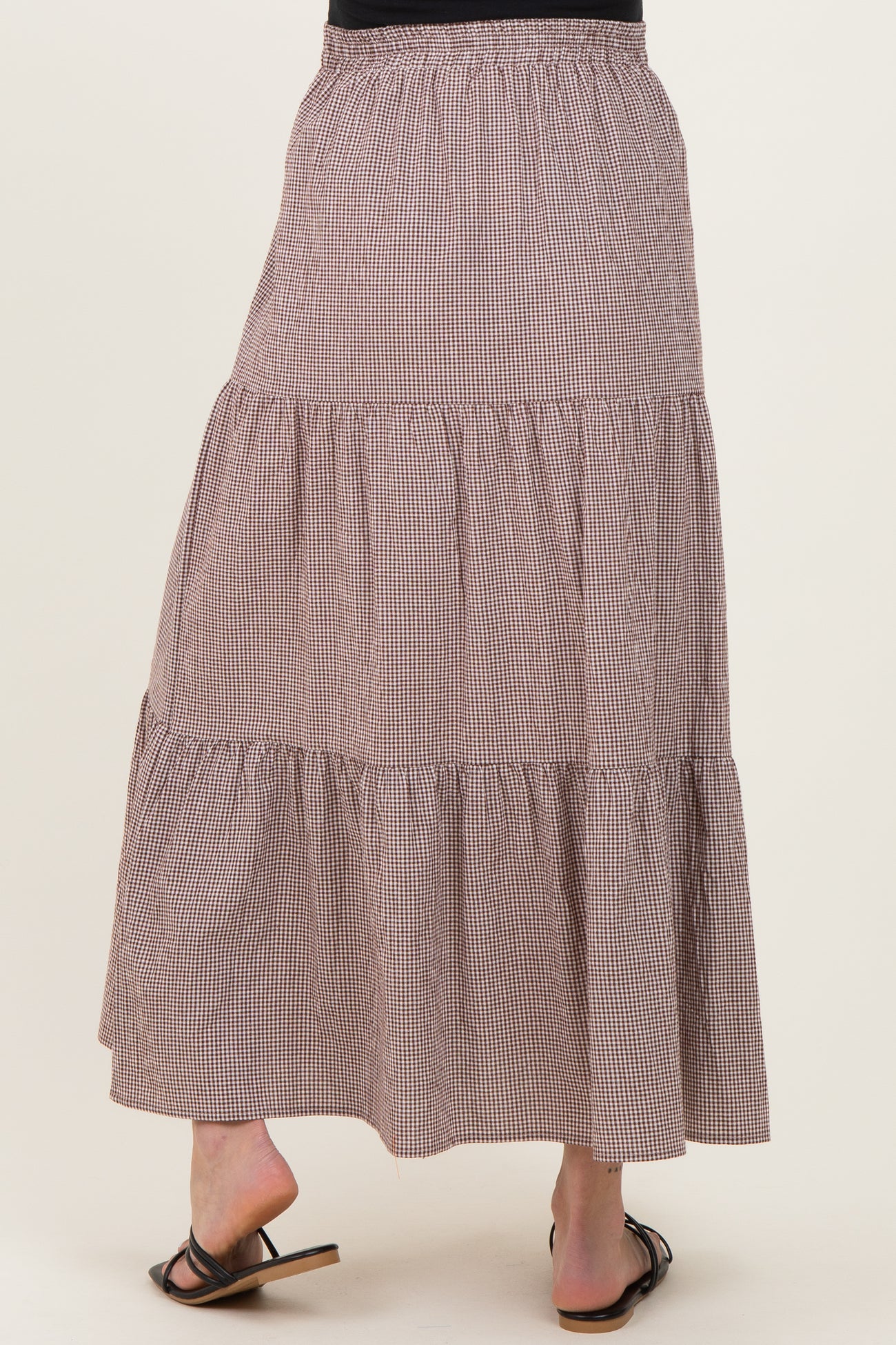 woman wearing a brown and white checked tiered maternity maxi skirt, showing the back view