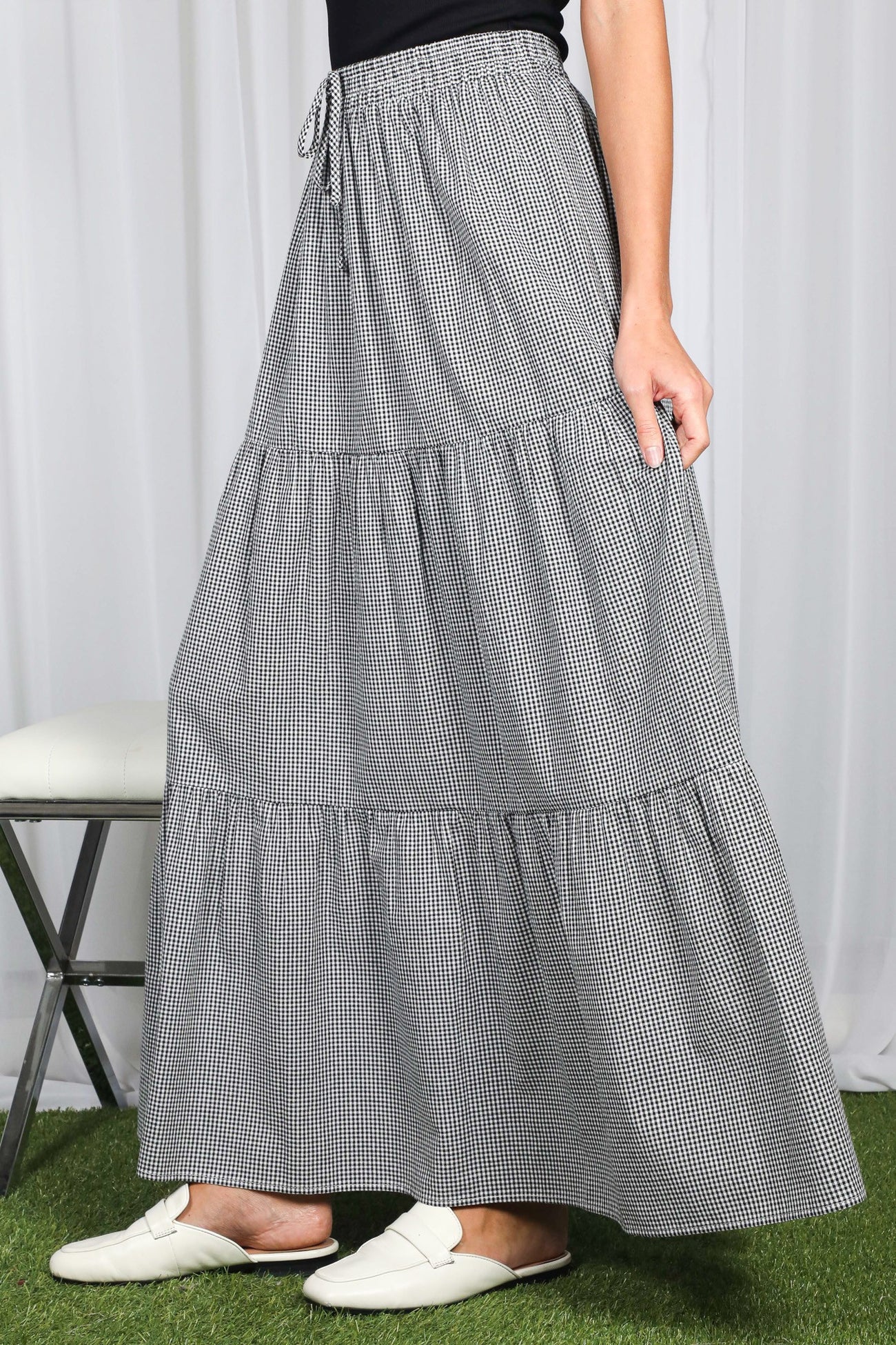 woman wearing a black and white checkered tiered maxi skirt with an elastic waistband and side pockets