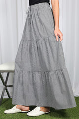 woman wearing a black and white checkered tiered maxi skirt with an elastic waistband and side pockets