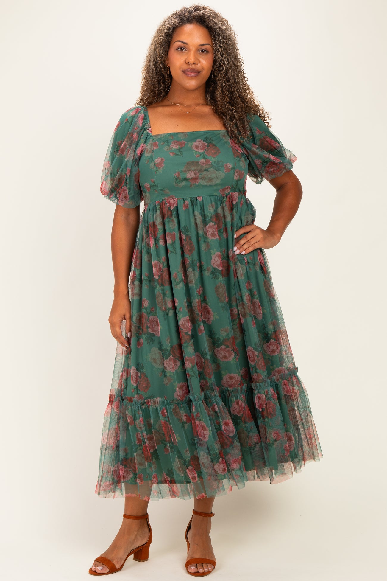 woman wearing a green floral midi dress with puff sleeves and a tiered skirt, styled with brown heeled sandals