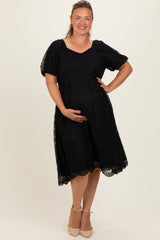 woman wearing a black lace maternity dress with short puff sleeves, showcasing her baby bump