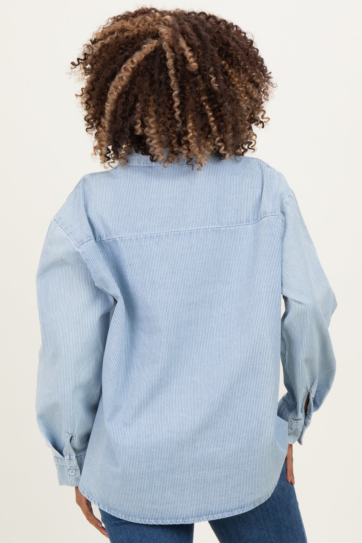 woman wearing a light blue maternity wear button-up shirt with a relaxed fit and long sleeves, showing the back view
