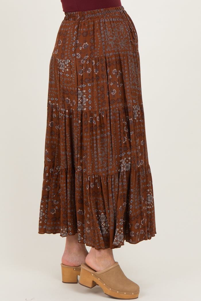 maternity wear rust colored maxi skirt with floral print and tiered design, model wearing a burgundy top and clogs