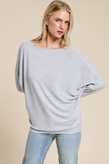 woman wearing a light grey oversized sweater with a loose fit and rolled sleeves, paired with light blue jeans
