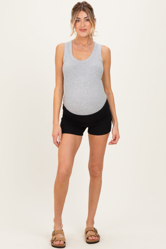 woman wearing a gray ribbed tank top and black maternity shorts, showing her baby bump