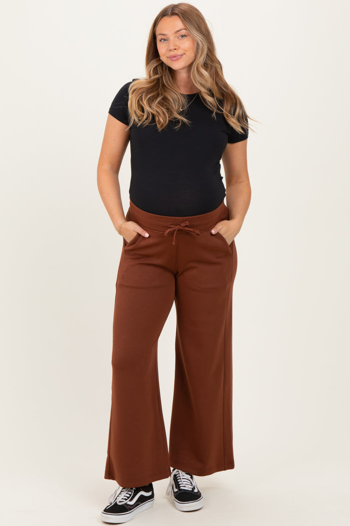 woman wearing a black maternity t-shirt and brown wide-leg maternity pants with pockets and drawstring, smiling